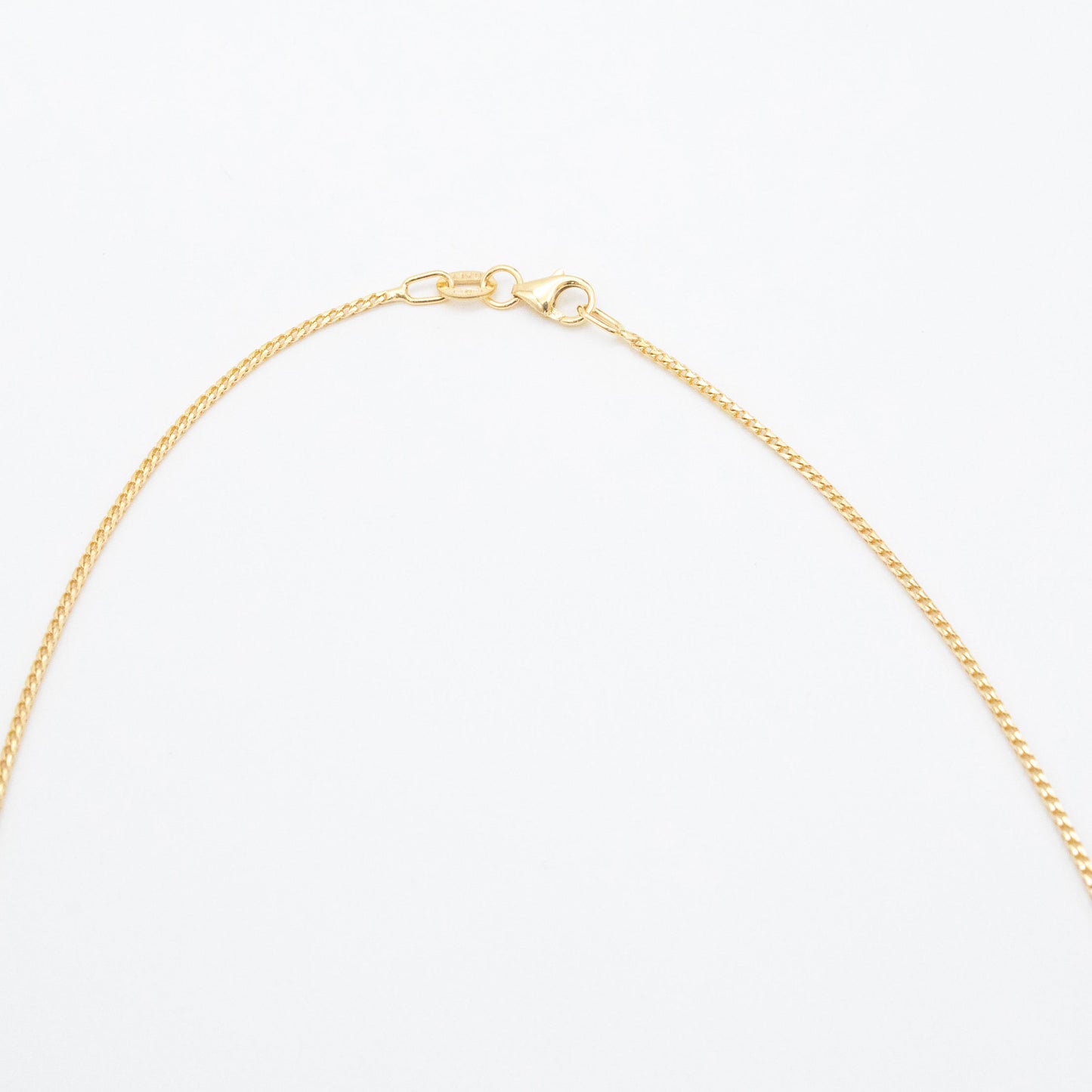 1.1mm Franco chain necklace in 9ct yellow gold laid flat on a white background with clasp visible