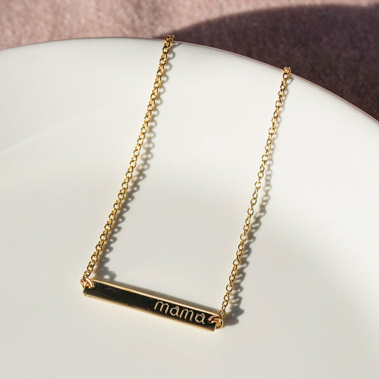 Close-up of a personalised yellow gold name plate bracelet showing its rectangular ID bar and fine chain.