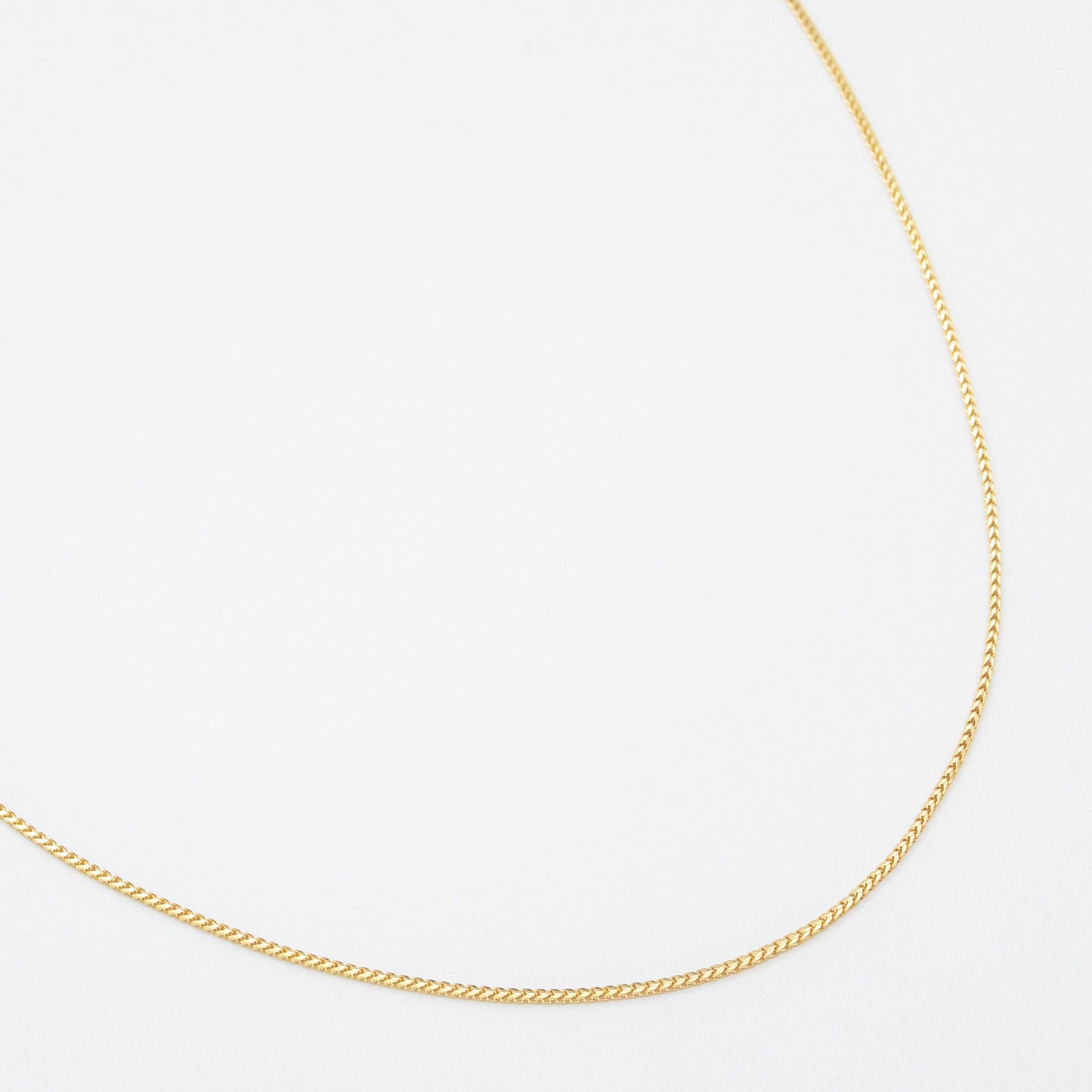 1.1mm Franco chain necklace in 9ct yellow gold laid flat on a white background.
