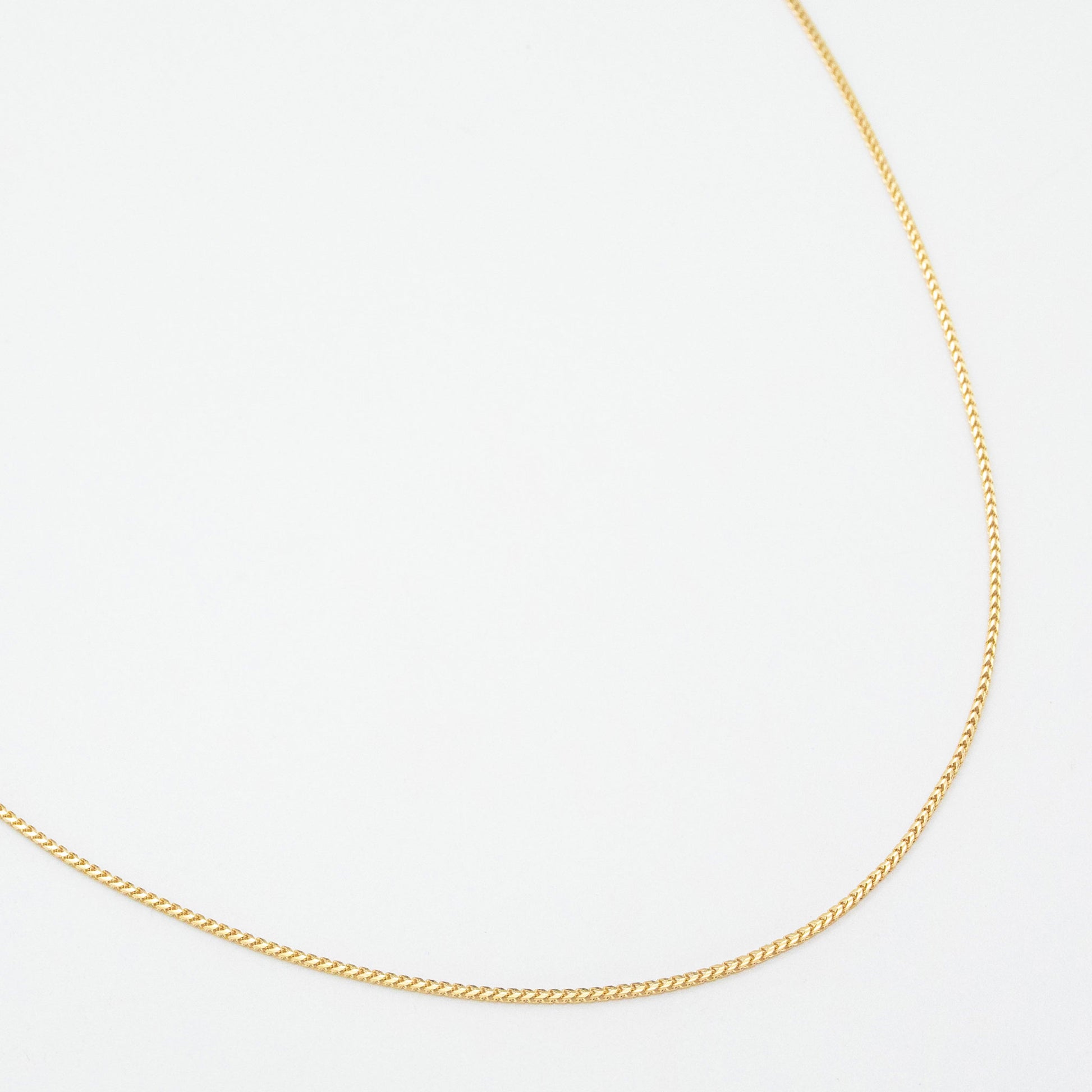 1.1mm Franco chain necklace in 9ct yellow gold laid flat on a white background.