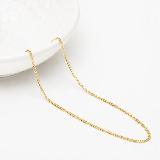 1.2mm curb link chain in 9ct yellow gold displayed on a white jewellery dish