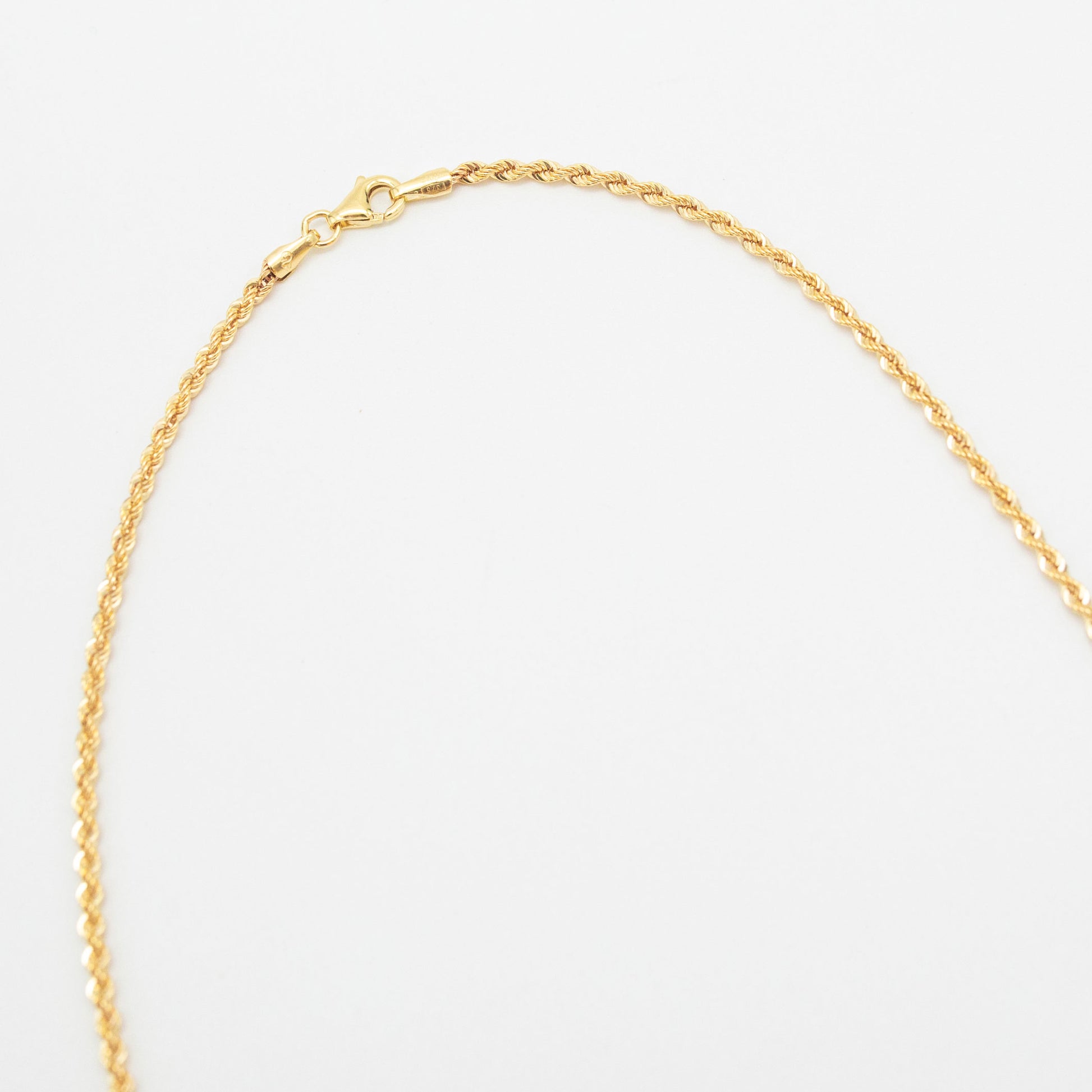 A 9ct yellow gold rope chain necklace laid out on a white background