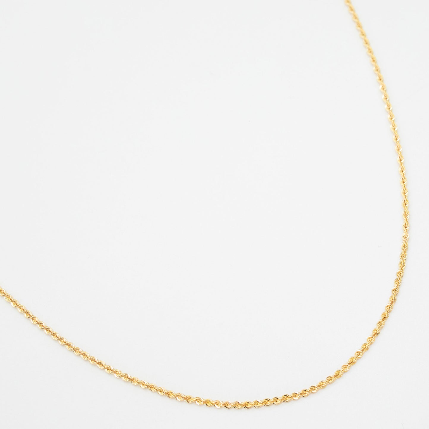 A 9ct yellow gold rope chain necklace laid out on a white background