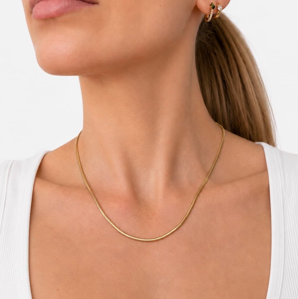 2.8mm flat snake chain in 9ct yellow gold worn around the neck