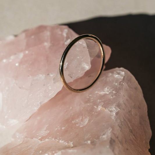 Close-up of a polished 9ct gold stacker ring photographed on a pink stone surface.