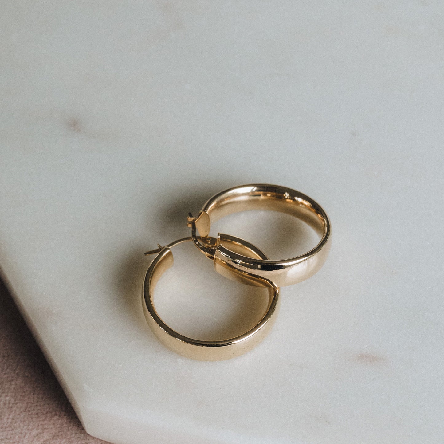 Small 9ct gold D-shape hoops displayed together on white background