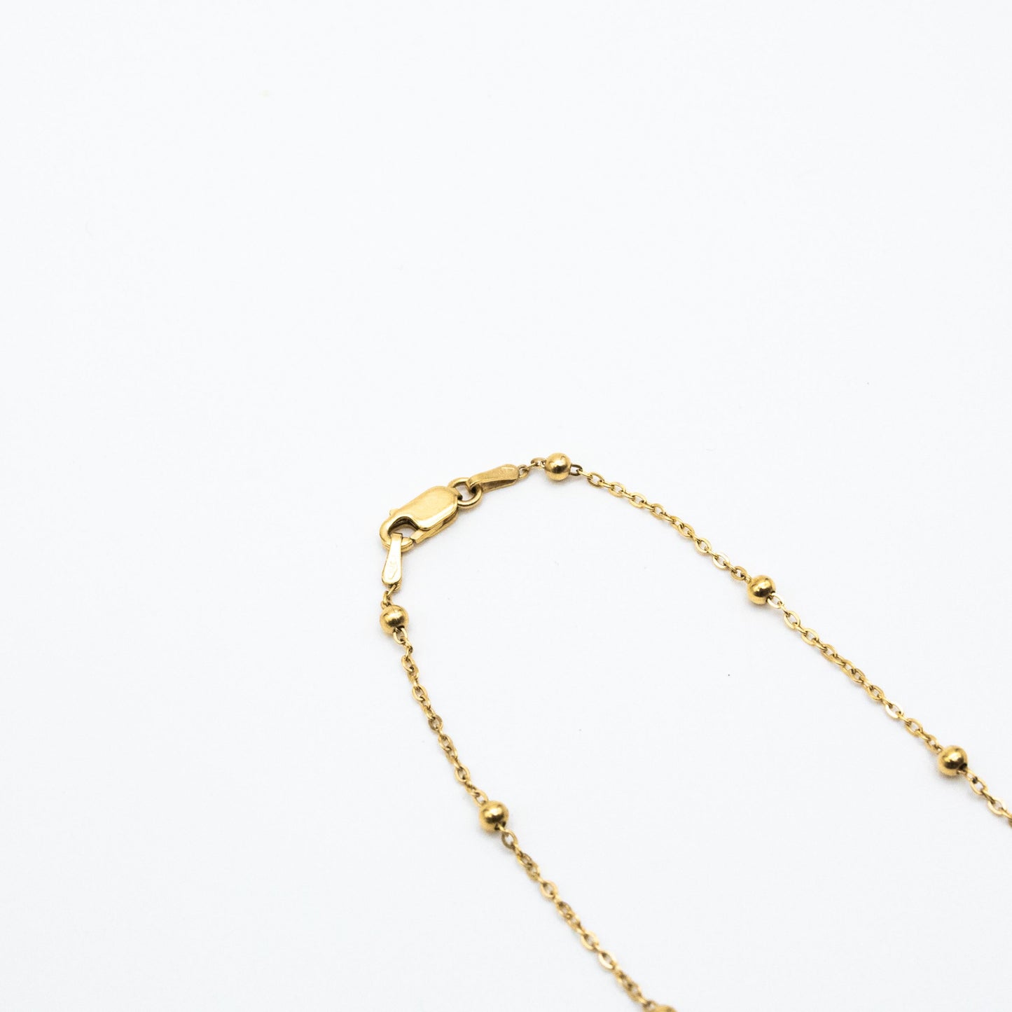9ct yellow gold dotted chain necklace with evenly spaced gold beads, laid flat on a white background showing clasp