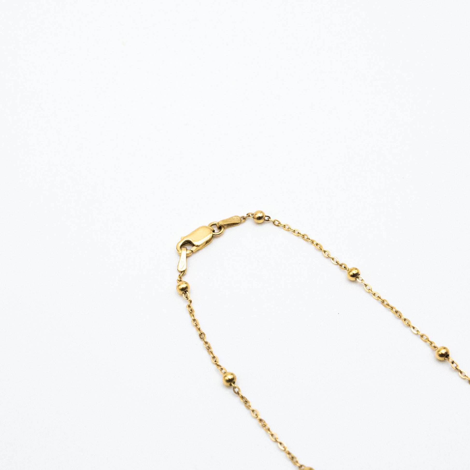 9ct yellow gold dotted chain necklace with evenly spaced gold beads, laid flat on a white background showing clasp