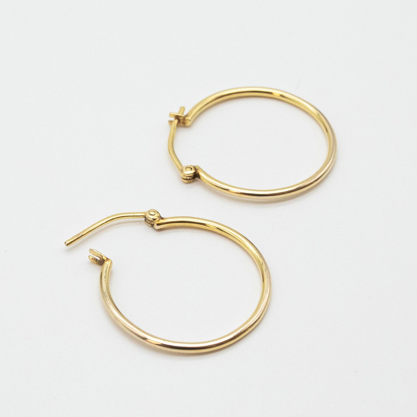 Medium gold hoops shown on linen fabric close-up.