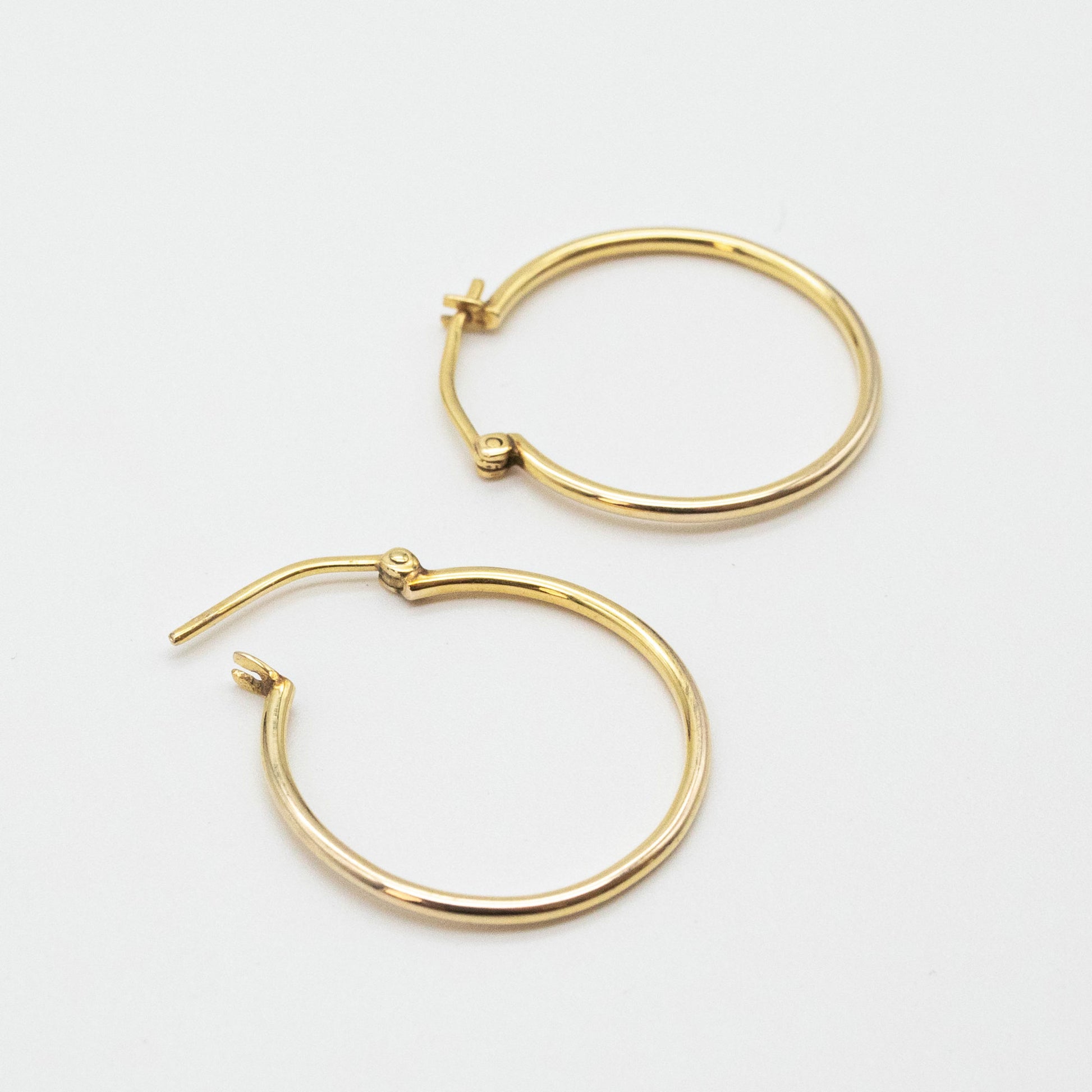 Medium gold hoops shown on linen fabric close-up.