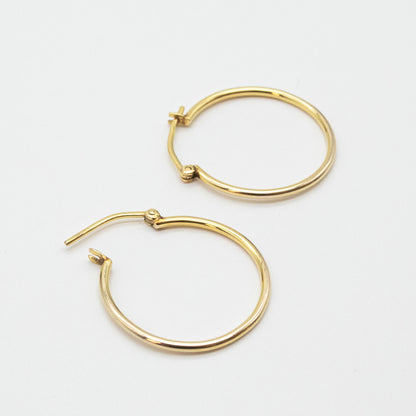 Medium gold hoops shown on linen fabric close-up.