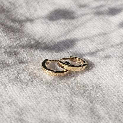 Single pair of mini gold huggies photographed on white background
