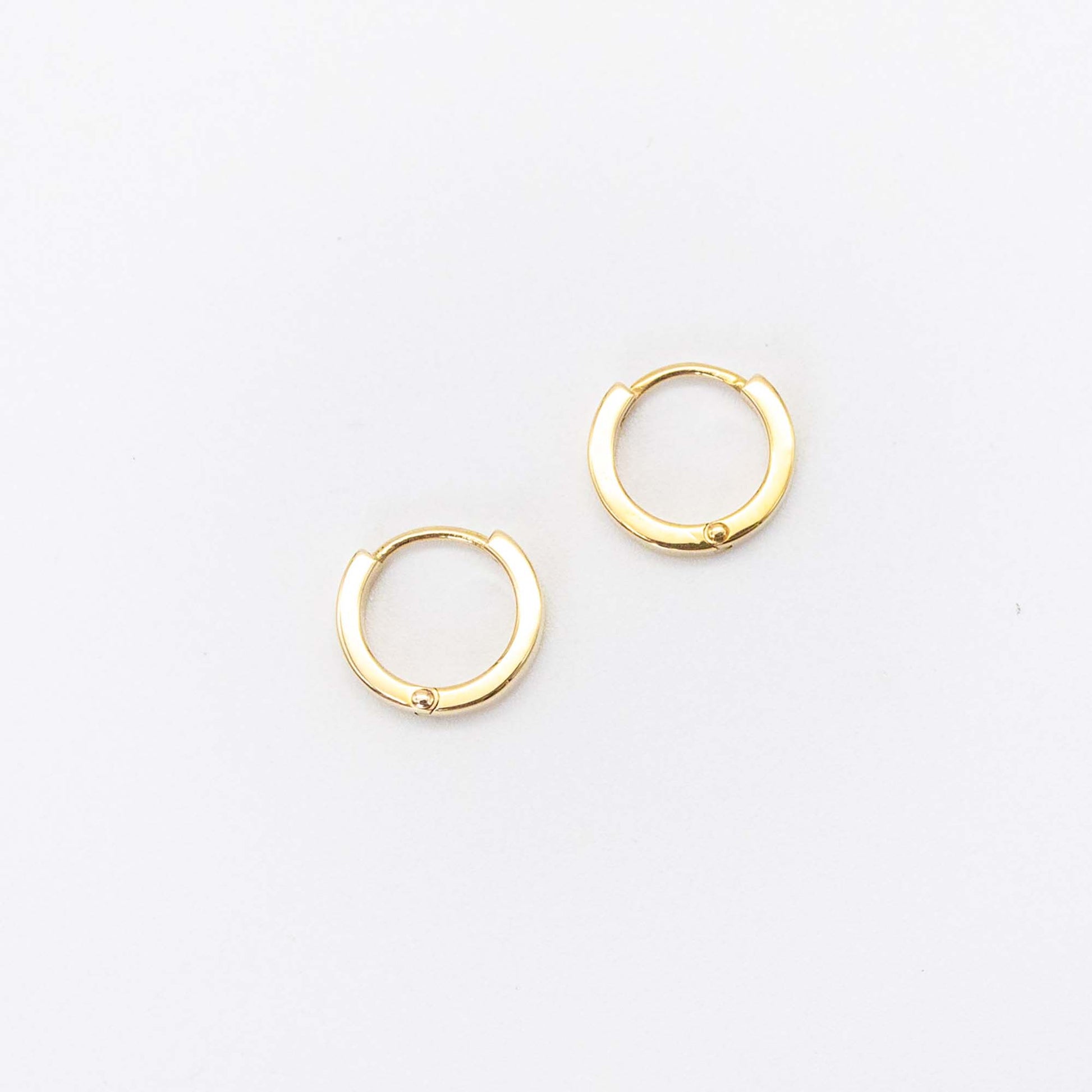 Single pair of mini gold huggies photographed on white background