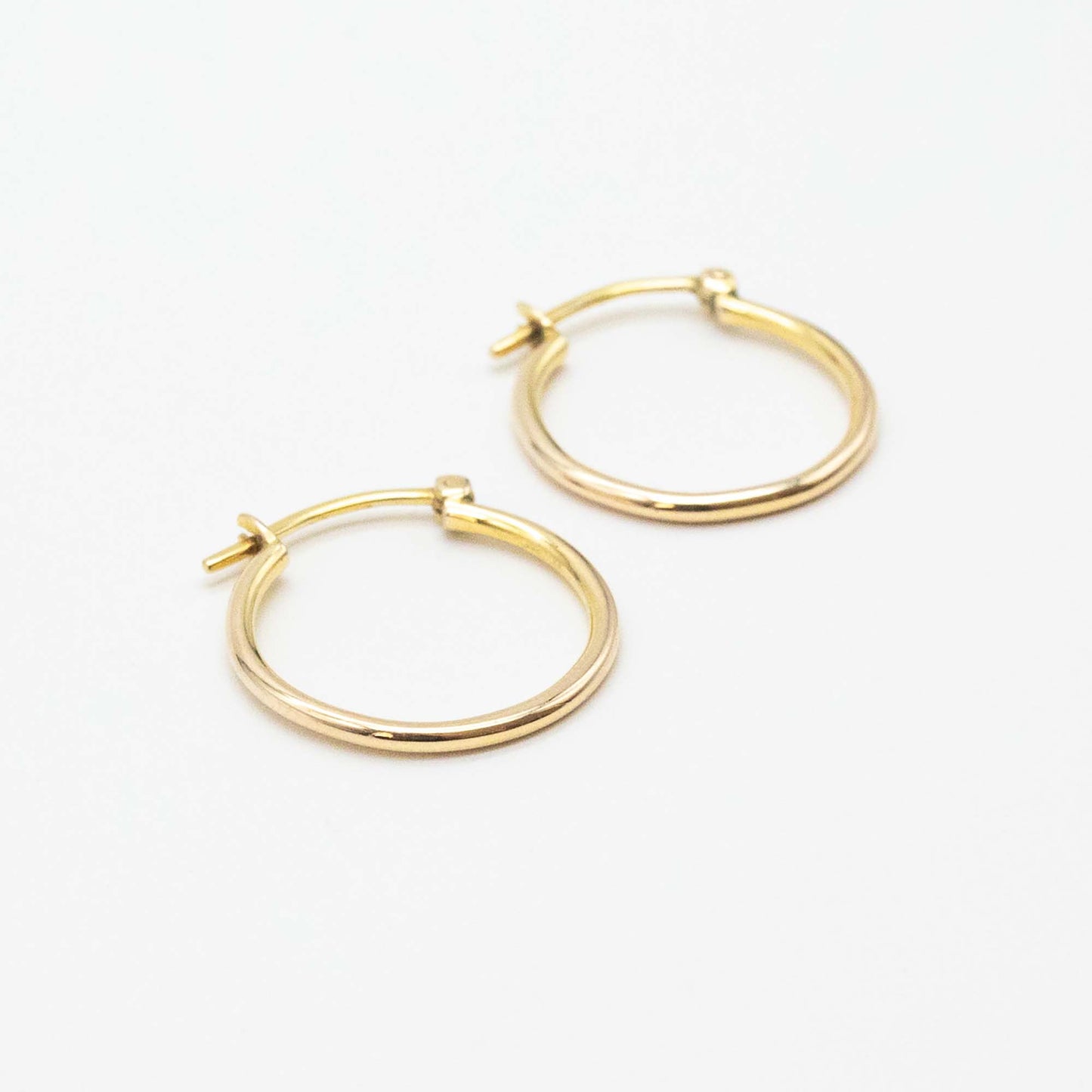 Close-up of 9ct gold small hoops highlighting polished shine and V-clip closure.