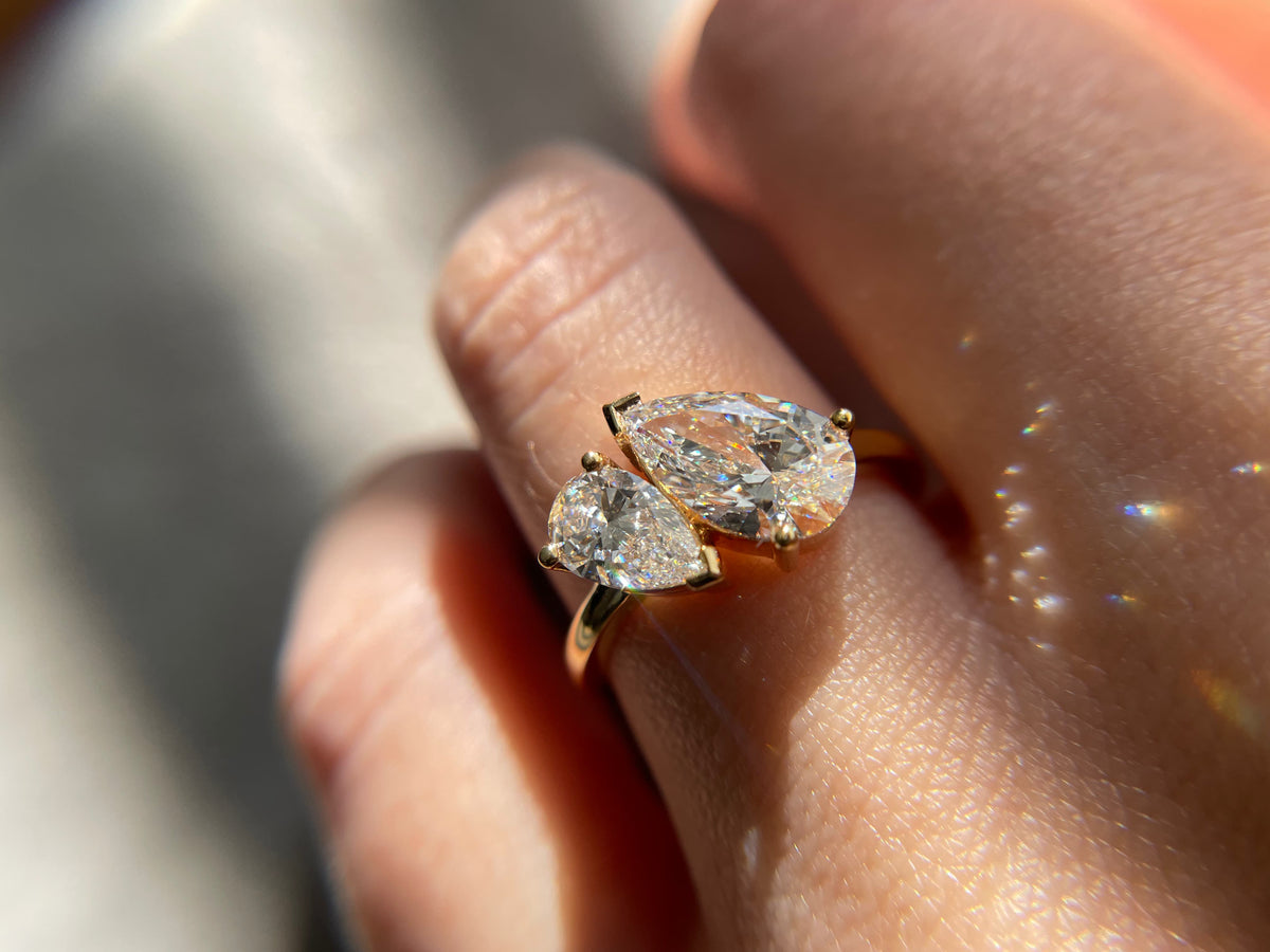 Pear-shaped diamond toi et moi engagement ring in yellow gold, featuring two pear-cut diamonds worn on a hand