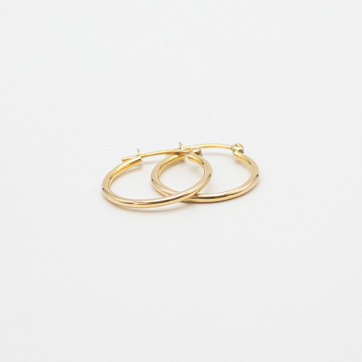 Close-up of 9ct gold small hoops highlighting polished shine and V-clip closure.