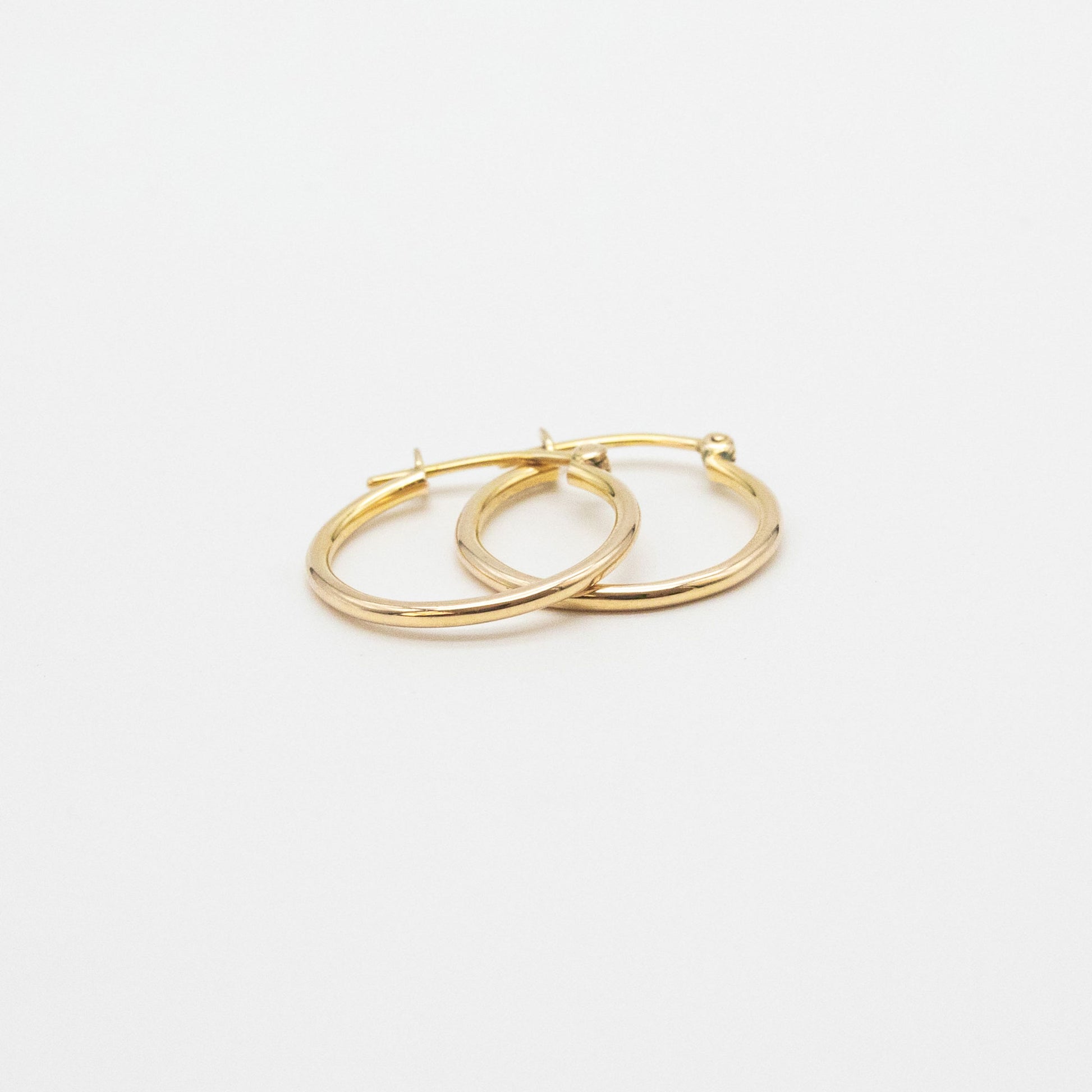 Close-up of 9ct gold small hoops highlighting polished shine and V-clip closure.