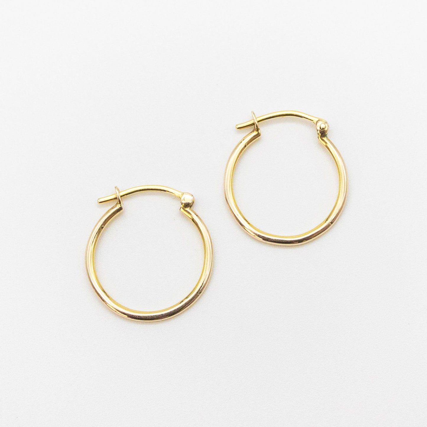 Close-up of 9ct gold small hoops highlighting polished shine and V-clip closure.