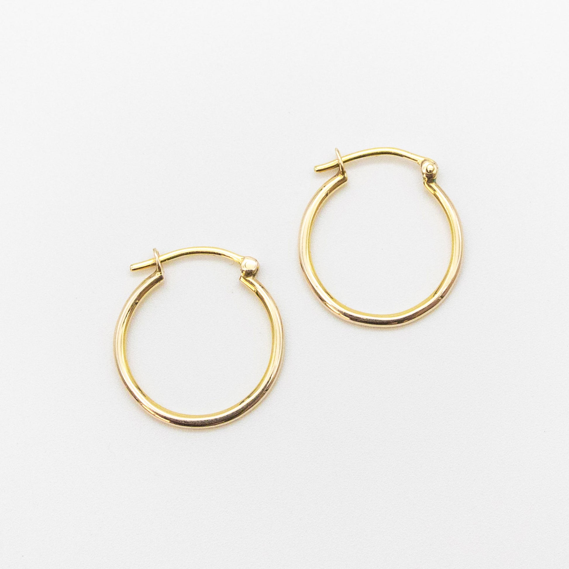 Close-up of 9ct gold small hoops highlighting polished shine and V-clip closure.