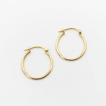 Close-up of 9ct gold small hoops highlighting polished shine and V-clip closure.