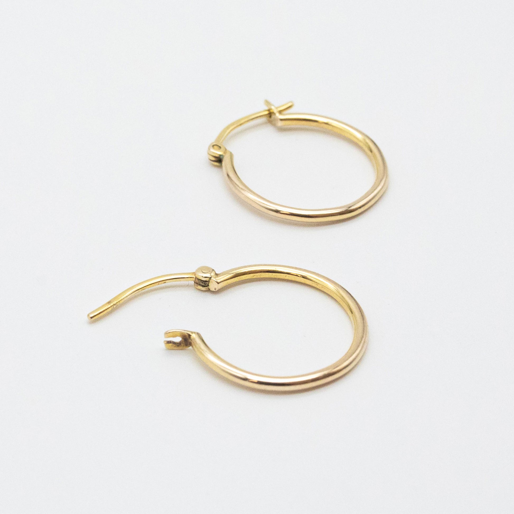 Close-up of 9ct gold small hoops highlighting polished shine and V-clip closure.